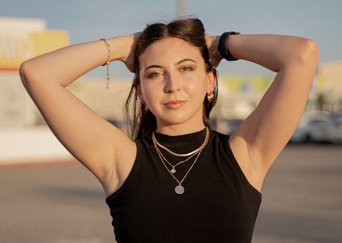 A stylish young woman poses confidently outdoors at sunset, embracing a casual summer vibe.